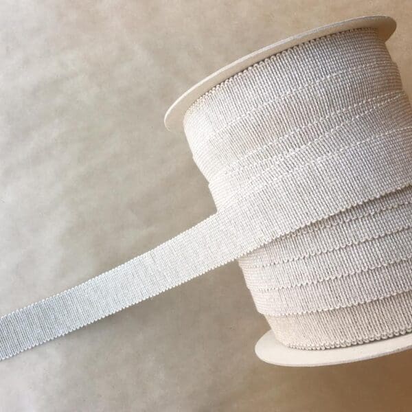 A spool of 1.5 IN Nail Head Tapes ribbon on a table.