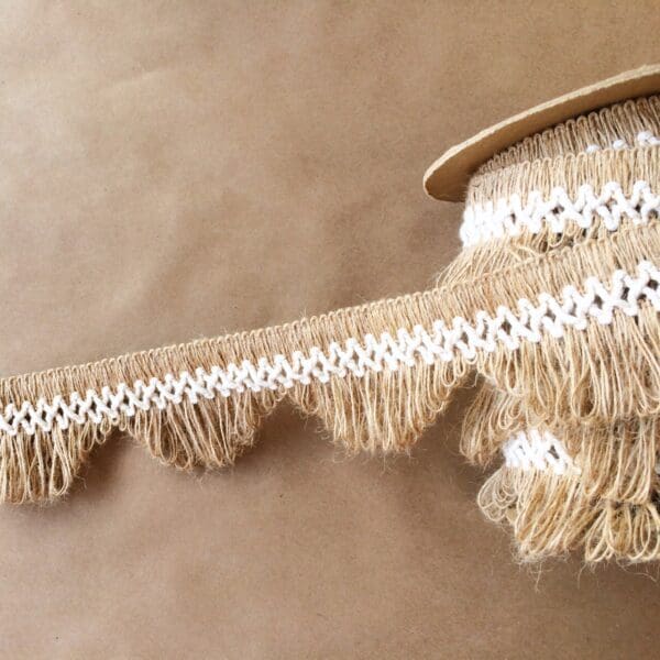 A piece of Scalloped Lace Fringe with white fringes on it.