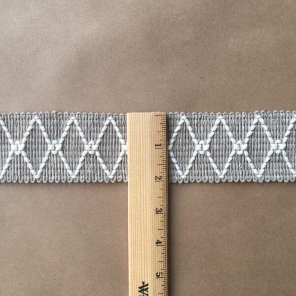 A Charleston Outdoor/Indoor Tapes next to a gray and white woven belt.