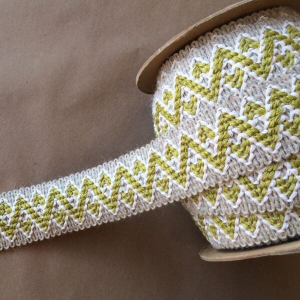 A yellow and white striped Chevron Wool ribbon on a table.