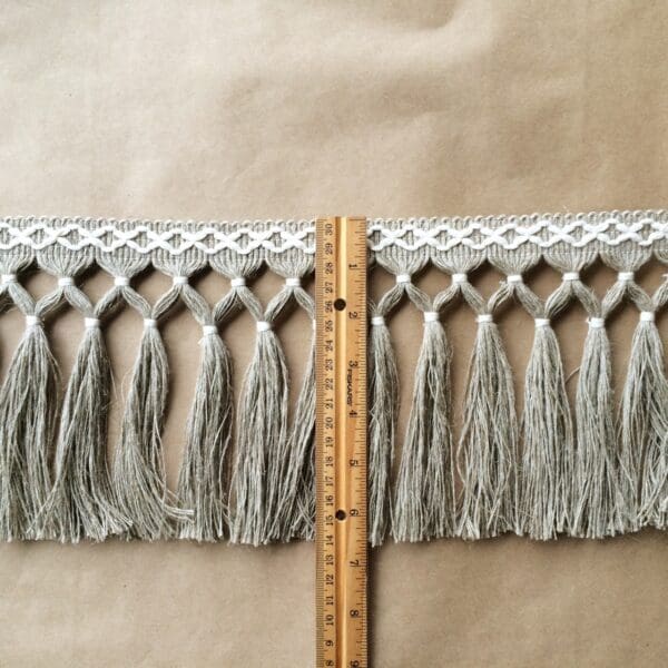 A Diamond Double Knot Fringe 6.5 measuring tape with tassels on it.