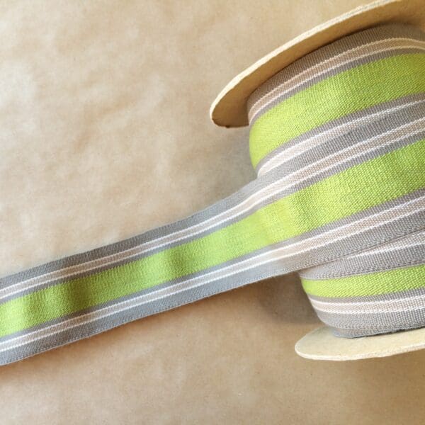 A green and grey striped Eden 2 1/4 ribbon on a table.