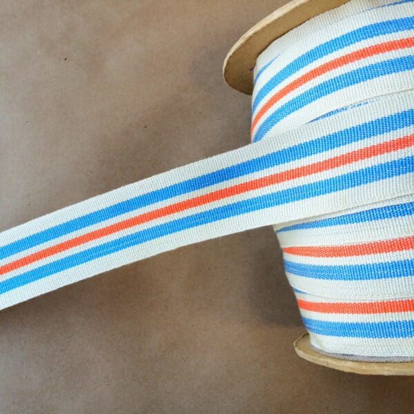 A blue and orange striped Eden 1.5 and 2IN Tapes-Indoor and Outdoor ribbon on top of a spool.