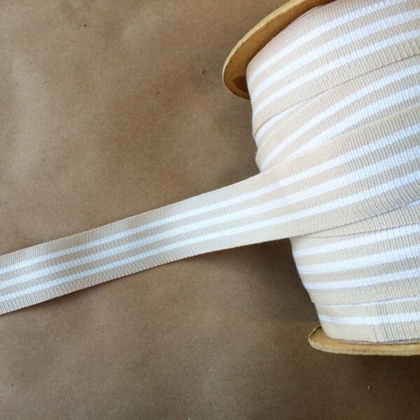 A white and beige Eden 1.5 and 2IN Tapes-Indoor and Outdoor striped ribbon on a table.