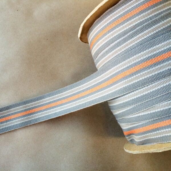 A grey and orange Eden 1.5 and 2IN Tapes-Indoor and Outdoor striped ribbon on a table.