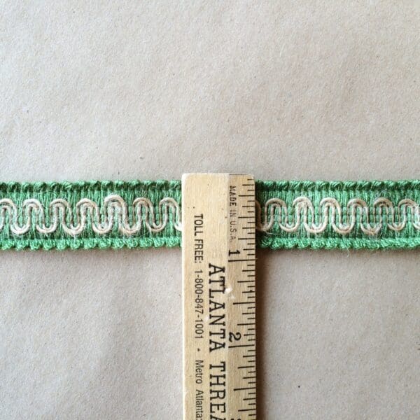 A green and white embroidered G-12 Gimps on a ruler.