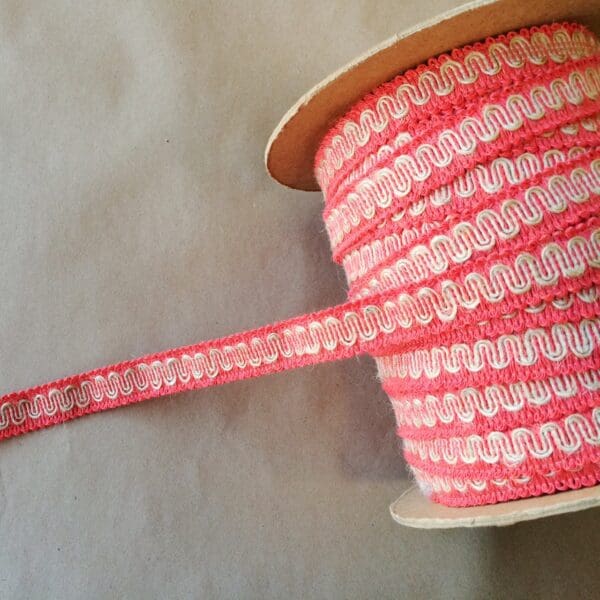 A pink and white spool of G-12 Gimps ribbon on a table.