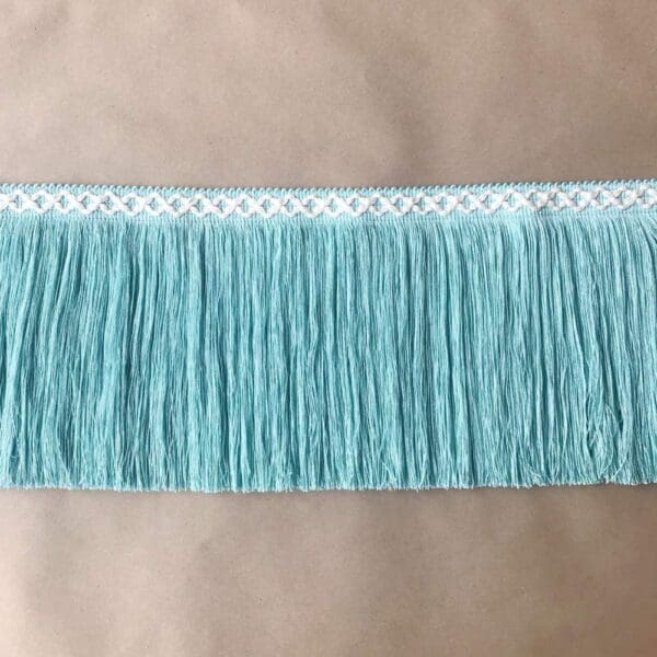 A turquoise fringe trim with white lace on it.