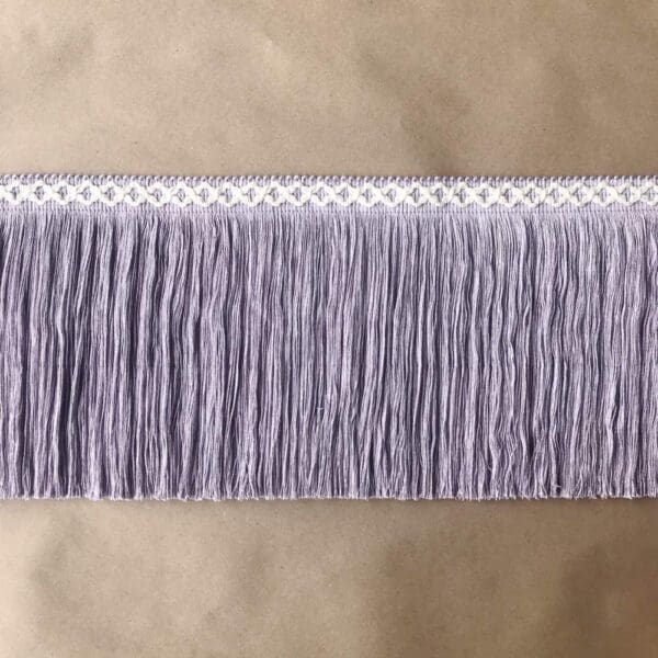 A purple fringe trim on a beige background.