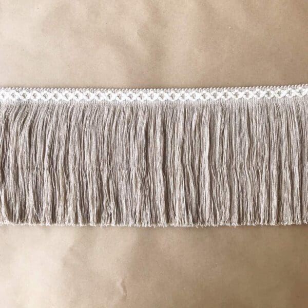 An image of a grey fringe trim on a table.