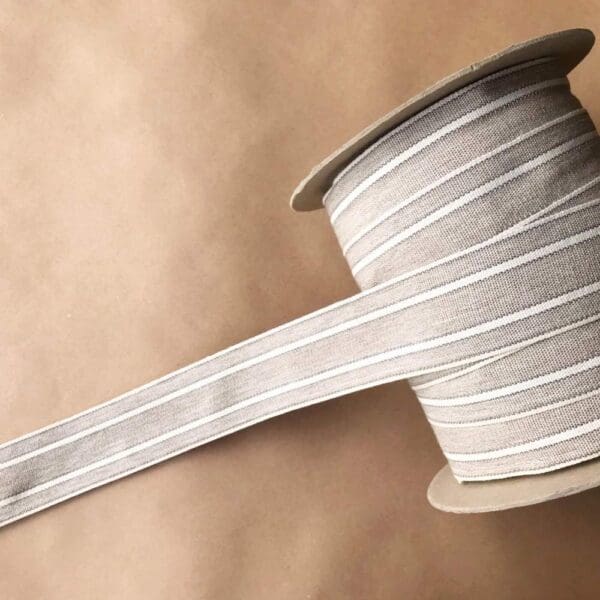 A spool of Balcony Outdoor Tapes beige and white striped ribbon.