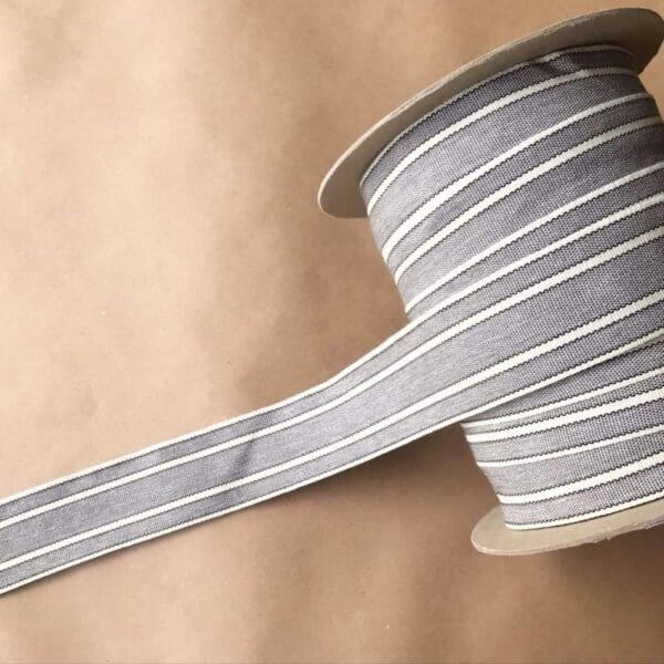 A grey and white striped Balcony Outdoor Tapes on a spool.