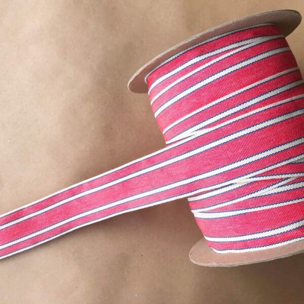 A pink and white striped Balcony Outdoor Tapes on a spool.