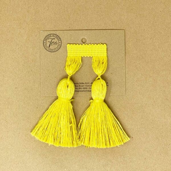 A pair of yellow 5IN Chunky Tassel Fringe on a card.