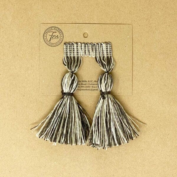 A pair of 5IN Chunky Tassel Fringe on a piece of cardboard.