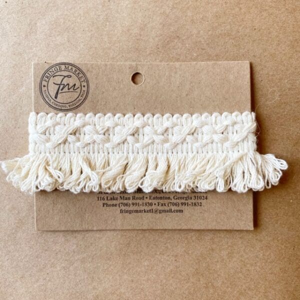 A Loopy Fringe 1.5 IN crochet tassel on a piece of cardboard.