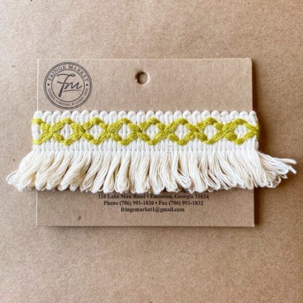 A white and yellow Loopy Fringe 1.5 IN on a piece of cardboard.