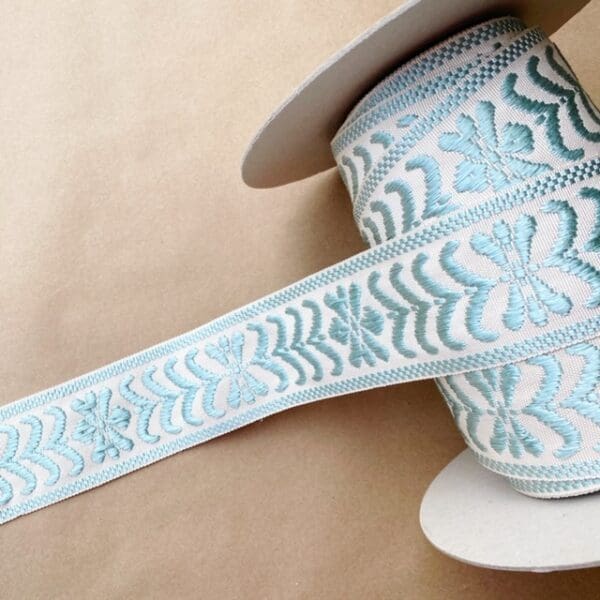 A roll of Park Avenue Silk Braid 2.5 IN blue and white embroidered ribbon.