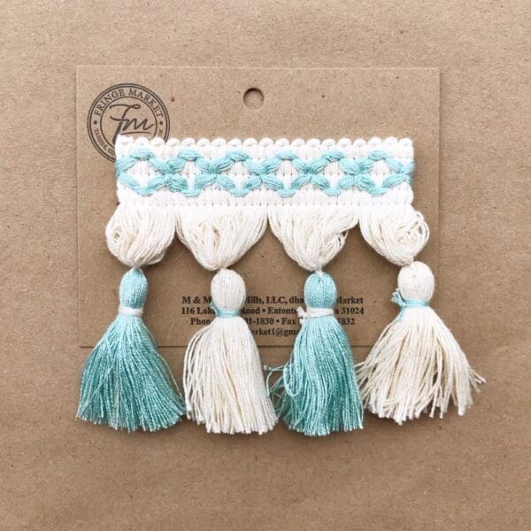 Frills Tassel Fringe 3.5 IN and white tassels on a piece of cardboard.