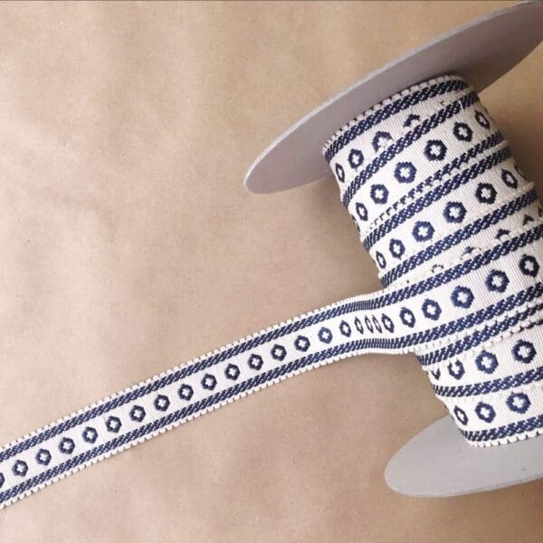 A spool of blue and white ribbon on a table.