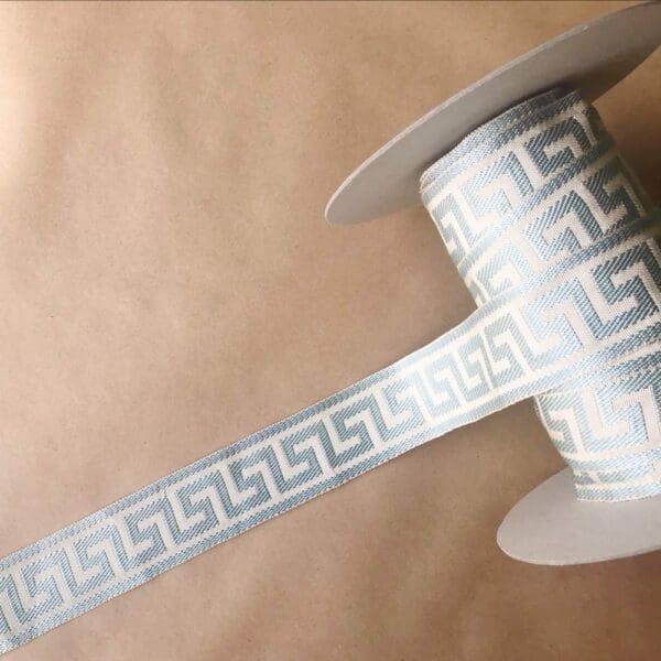 A roll of Greek Key Silk 2 1/4 IN ribbon with a greek design on it.