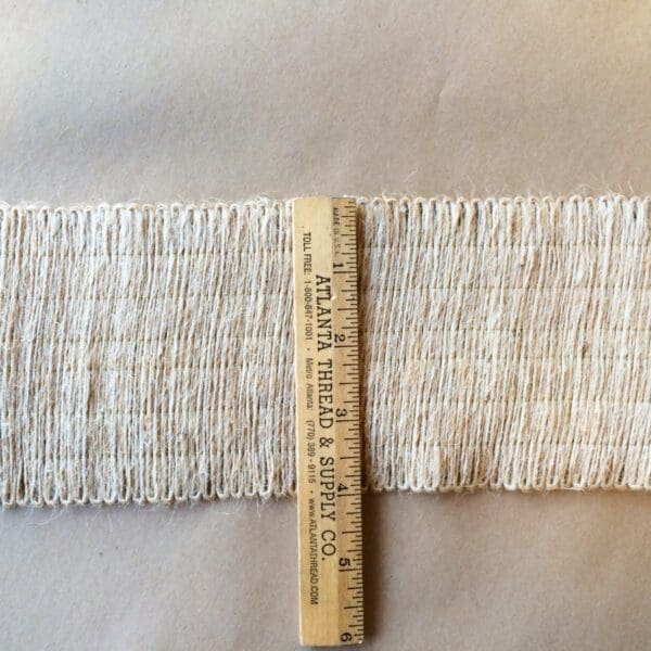 A ruler next to a Jute 4IN Webbing.