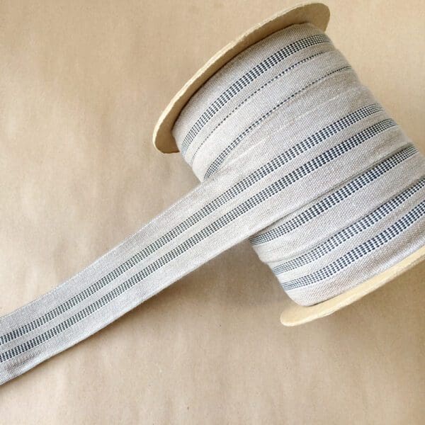 A spool of Modern Grain Sack striped ribbon on a table.