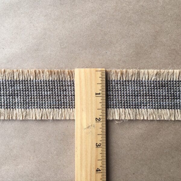 A Navajo Jute Tapes 2IN is used to measure the length of a piece of tweed.
