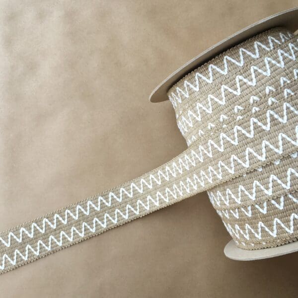 A roll of Essex Outdoor Tapes 2IN chevron ribbon on a brown surface.