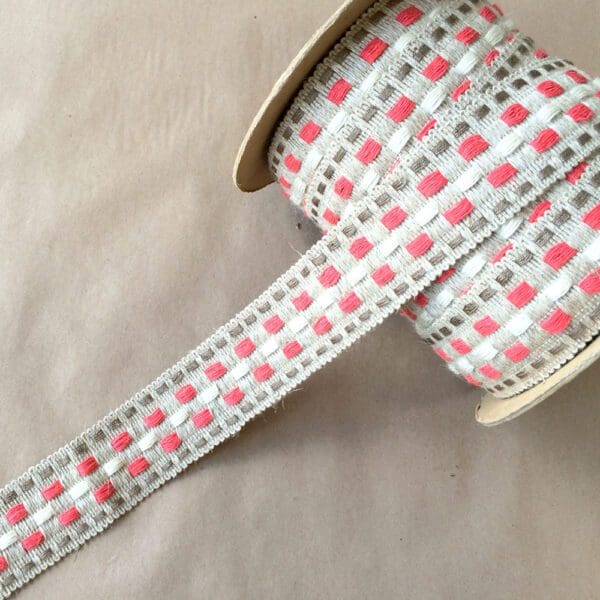A pink and white checkered Rio Braids ribbon on a table.