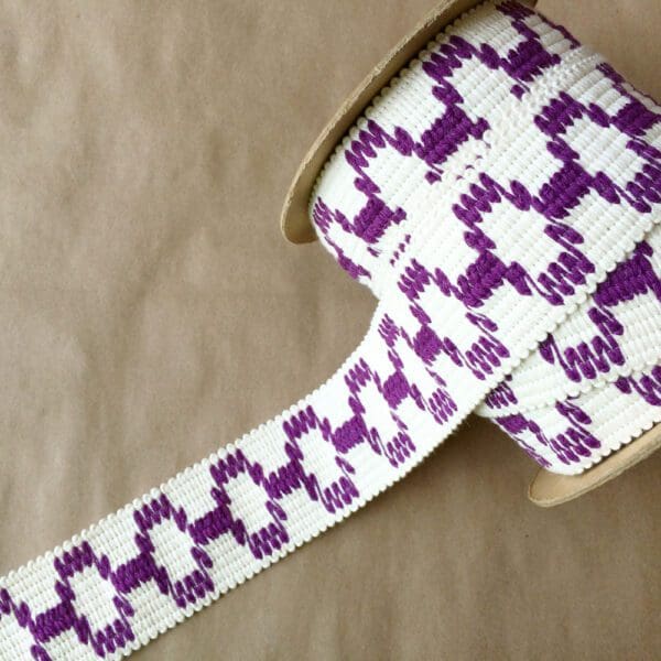 A purple and white Soho 2 1/4 woven ribbon on a table.