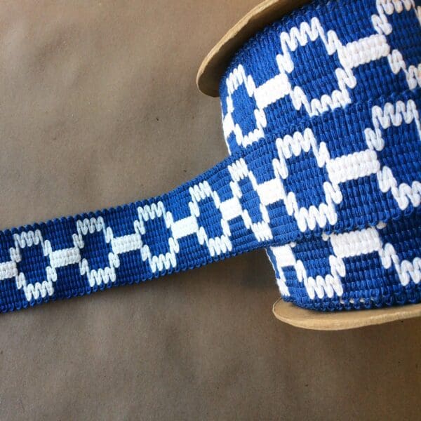 A blue and white Soho 2 1/4 braided ribbon on a table.