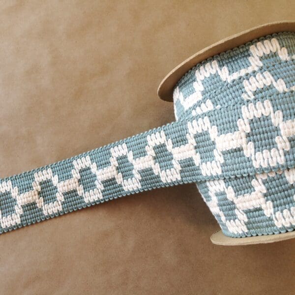 A Soho 2 1/4 blue and white woven ribbon on a table.