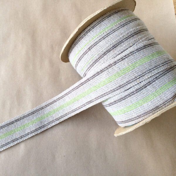 A grey and green striped Vintage Webbing on top of a table.