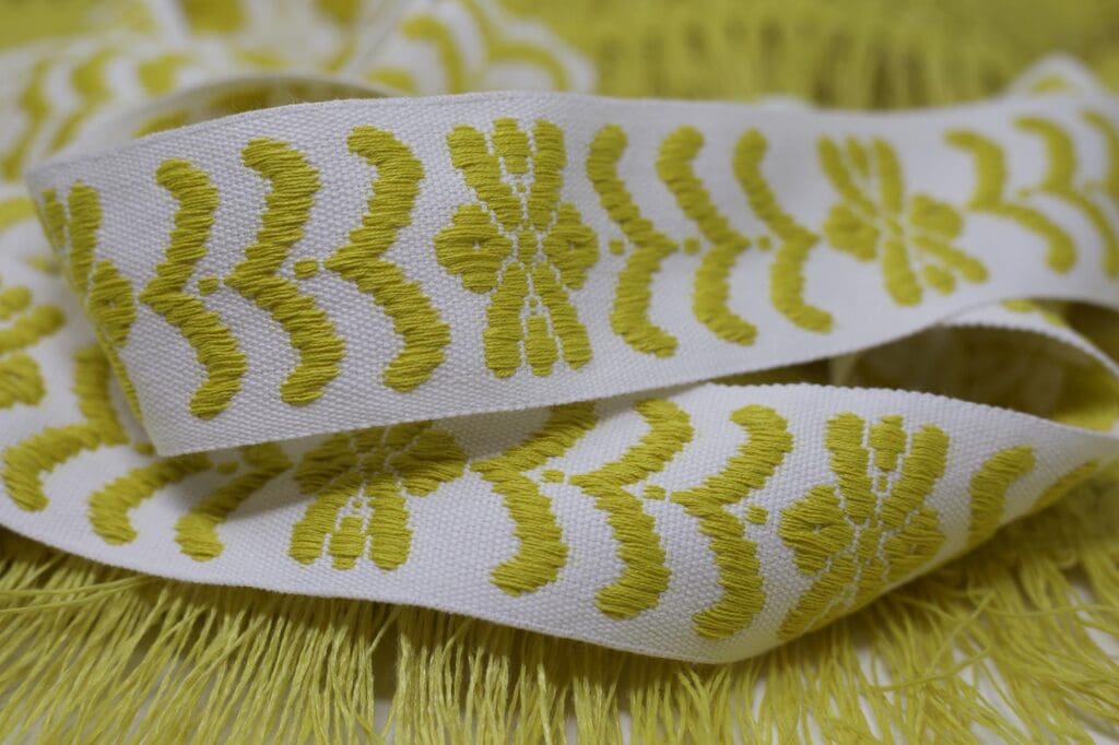 A close up of a yellow and white embroidered ribbon.
