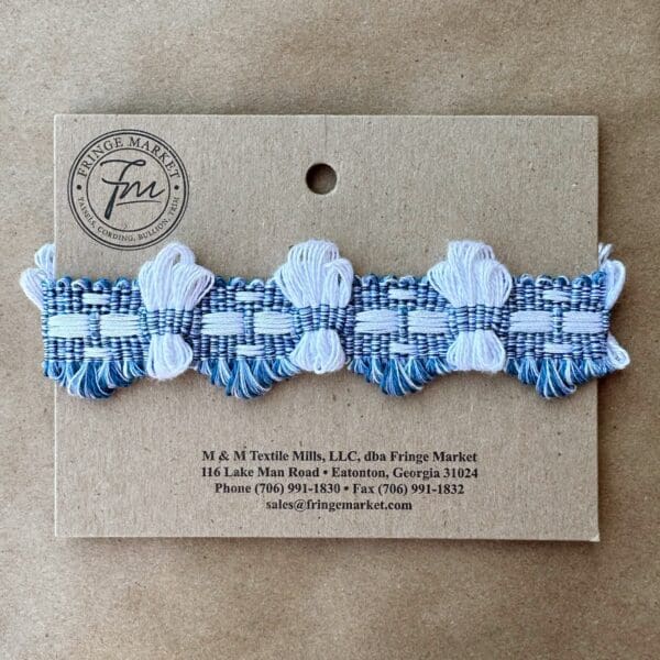 A blue and white Brooklyn Braids ribbon on a card.