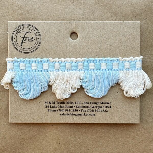 A blue and white Lenox Loop Fringe tassel on a piece of paper.