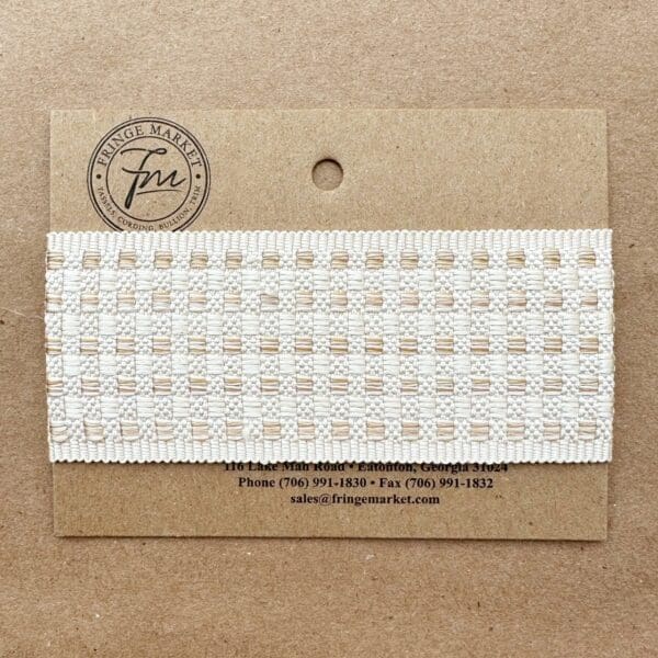 A Tabby Braid 2in lace ribbon affixed to a cardboard backing with the manufacturer's details printed below.