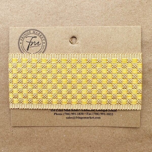 Yellow and white checkered Tabby Braid 2in sample attached to a cardboard label with contact information for Fringe Market.