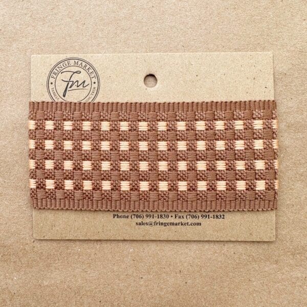 A beige card displaying a sample of Tabby Braid 2in trim labeled "Fringe Market" with contact information printed below.