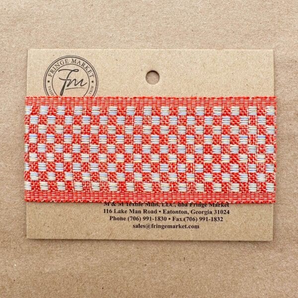 A Tabby Braid 2in tag with a woven red and white fabric band, featuring a logo and contact information for Fringe Market.