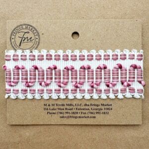 A row of pink and white twisted Belvoir Silk Braids arranged neatly on a cardboard label from Fringe Market, including contact information and address.